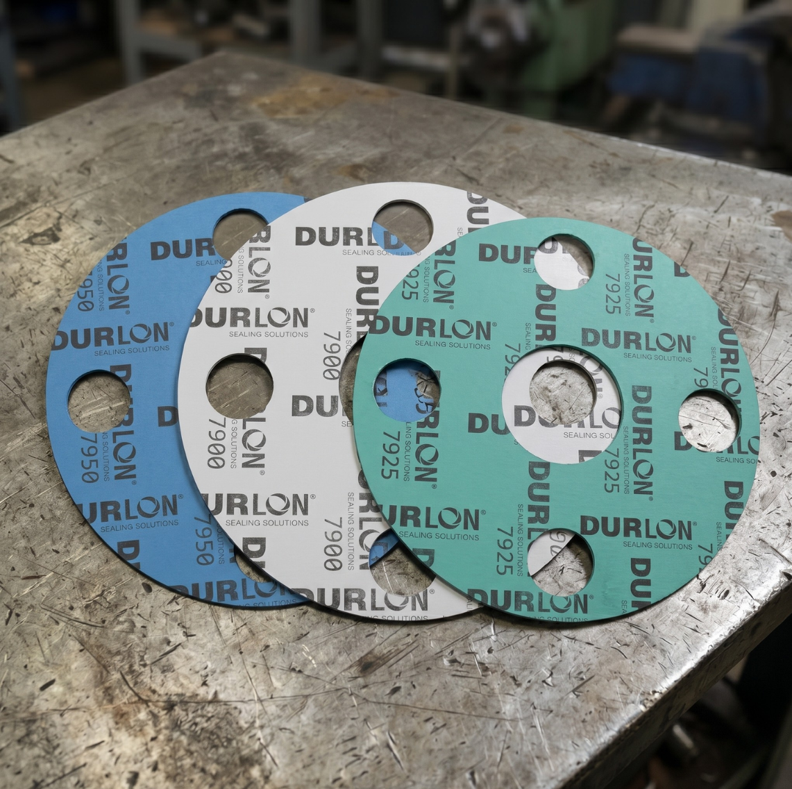 Durlon gasket materials 7900 7925 and 7950 shown as overlapping compressed non-asbestos gaskets on an industrial workbench