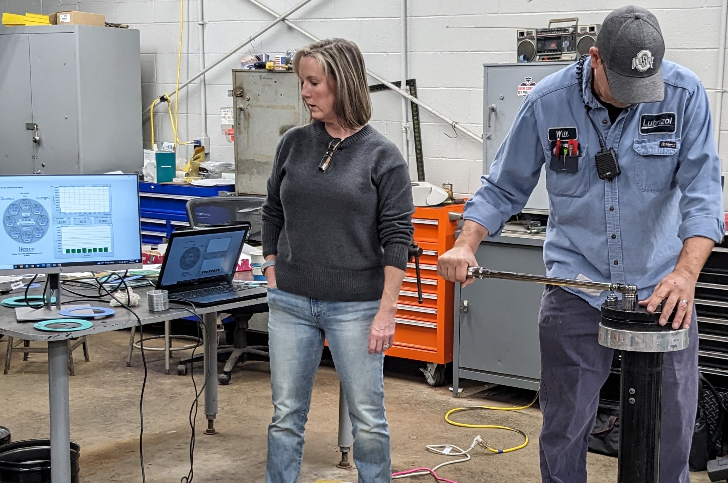 Technician performing gasket installation training using torque wrench on flange assembly demonstration unit with instructor observing